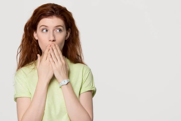 Shocked redhead woman cover mouth with hands looking at copyspace — Stock Photo, Image