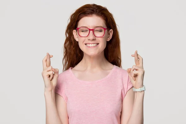 Heureux drôle jeune rousse fille étudiant croiser les doigts faire souhait — Photo