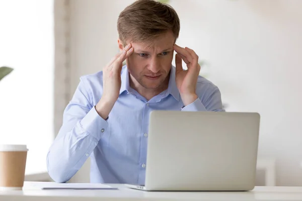 Hombre de negocios cansado sentado en el escritorio sufriendo de dolor de cabeza —  Fotos de Stock