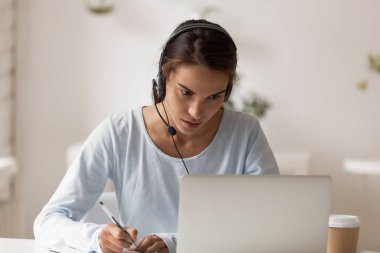 Focused on learning female wearing headset looking at computer screen clipart