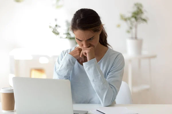 Gloomy young woman sitting at desk looking at computer screen — Stock Photo, Image