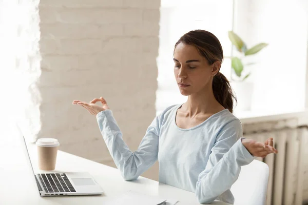 Young mixed race female sitting at workplace meditating — Stock Photo, Image