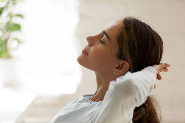 Mujer con los ojos cerrados poniendo las manos detrás de la cabeza descansando — Foto de Stock