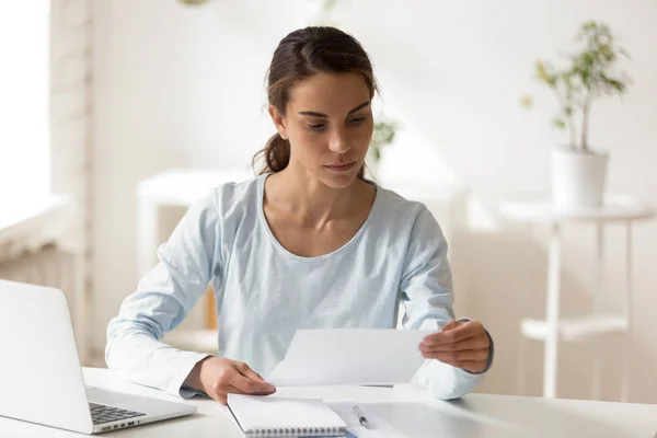 Mujer seria sentada en el escritorio leyendo carta — Foto de Stock