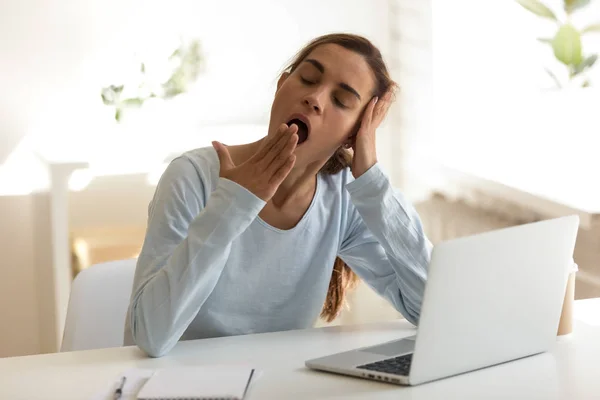 Verveeld vrouw zitten op werkplek voelt slaperig putting hoofd in haar hand — Stockfoto