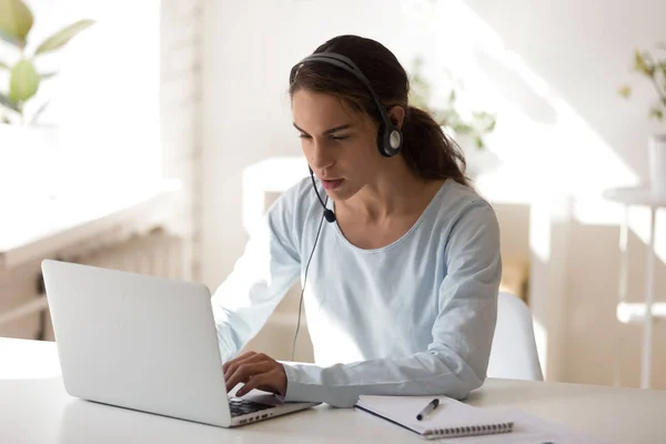 Perempuan muda belajar online menggunakan headset dan komputer — Stok Foto