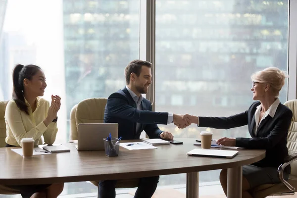 Felice dirigente di mezza età stringere la mano nuovo partner maschile alla riunione di squadra — Foto Stock