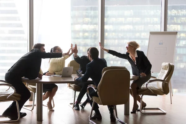 Diverse executive business team give high five in modern office