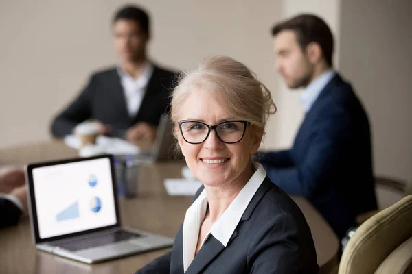 Heureuse femme d'affaires d'âge moyen dans des lunettes posant à la réunion du bureau de l'équipe — Photo