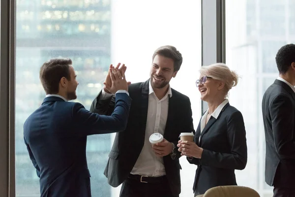 Los ejecutivos felices dan choca esos cinco durante una charla amistosa en la oficina — Foto de Stock