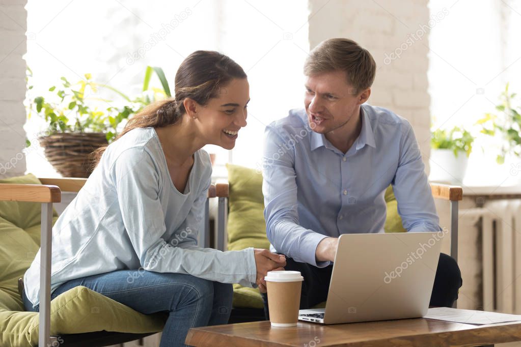 Couple of freelancers sitting on comfortable chairs working using laptop 