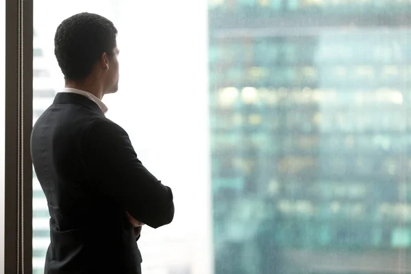 Rear view of successful african businessman standing looking at window — Stock Photo, Image