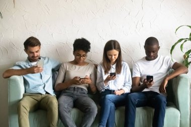 Akıllı telefonlar tarafından absorbe kanepede oturan dört genç insanlar