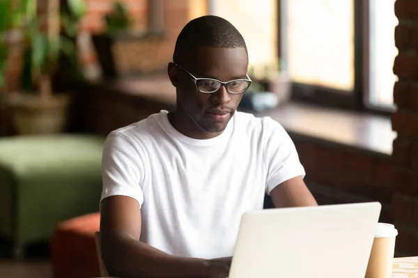 Сосредоточенный чернокожий парень, работающий за компьютером — стоковое фото