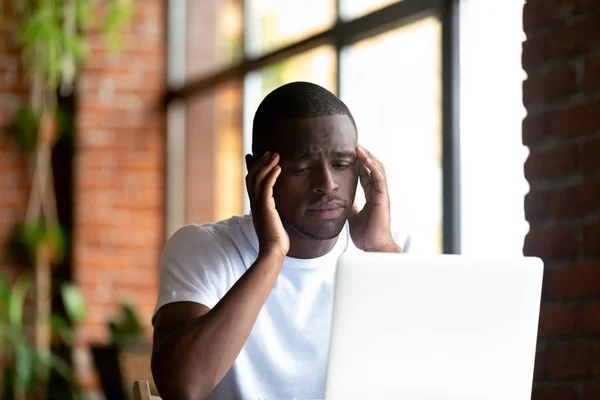 Βαρεθεί μαύρο νεαρός άνδρας κοιτάζοντας οθόνη υπολογιστή — Φωτογραφία Αρχείου