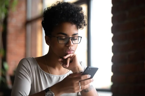 Mujer seria de raza mixta navegando por Internet usando el teléfono — Foto de Stock