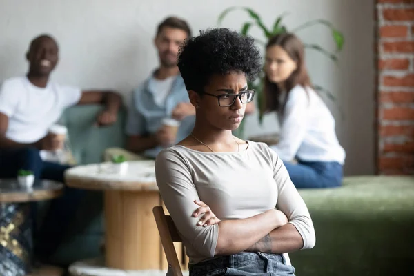 Черная девушка изгоя сидя отдельно от сверстников в кафетерии — стоковое фото