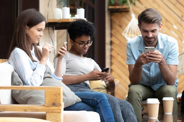 Les jeunes assis ensemble dans un café surfer sur Internet à l'aide de téléphones — Photo