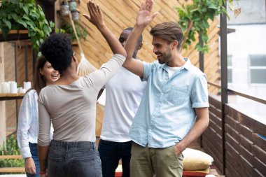 Çak bir beşlik veren yaz terasında duran çok ırklı insanlar