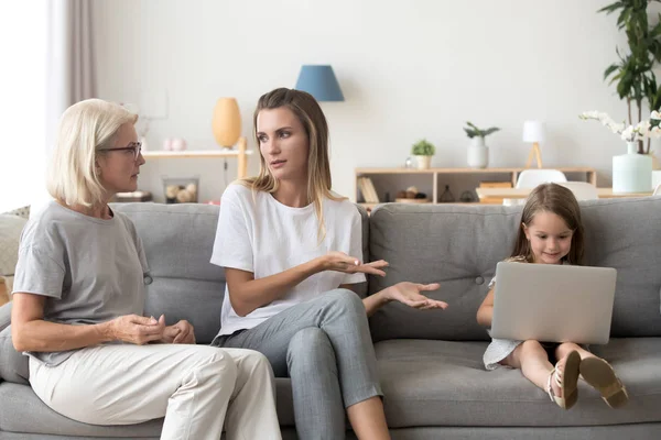 Madre e nonna discutendo piccola figlia dipendenza dal computer — Foto Stock