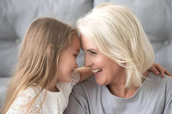 Gelukkig oma en kleindochter omarmen, raken voorhoofd — Stockfoto