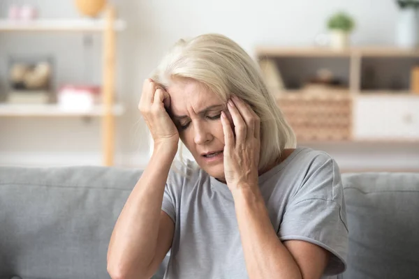 Close up aged woman suffering from headache, touching head — Stock Photo, Image