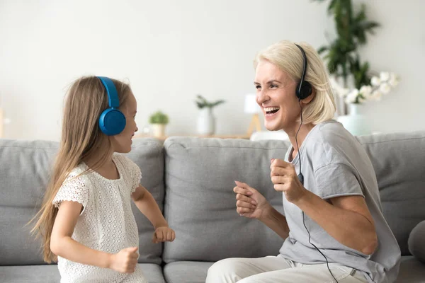 Nenek yang gembira dengan cucu di headphone mendengarkan musik — Stok Foto