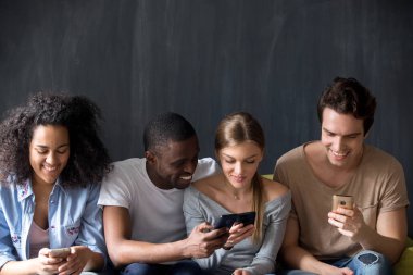 Gülümseyen çok ırklı arkadaş telefonları birlikte kullanarak, haber paylaşımı