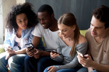 Telefonları birlikte kullanarak sırada, oturan mutlu çok ırklı insanlar