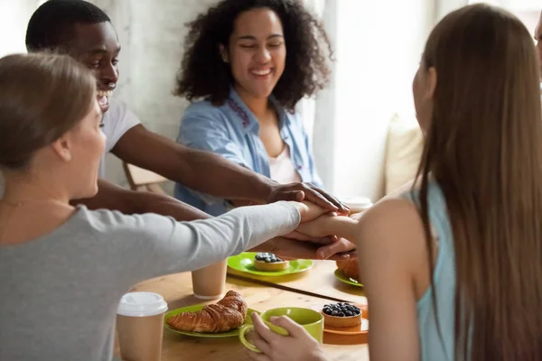 Happy glimlachend multiraciale vrienden toetreden tot handen tijdens bijeenkomst in café — Stockfoto