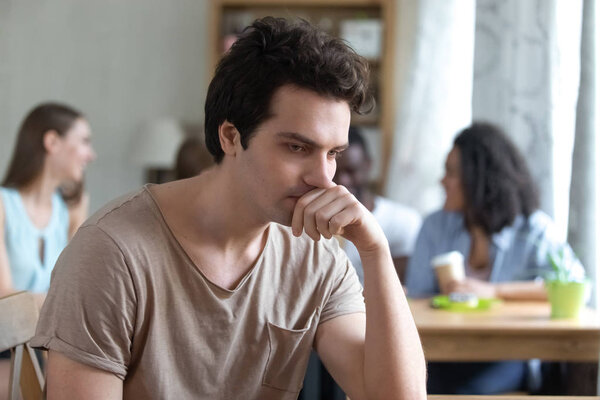 Расстроенный вдумчивый мужчина, сидящий один, с низкой самооценкой, у него нет друзей.
