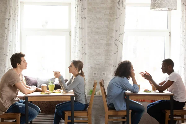 Young multiracial people sitting and drinking coffee in cozy cafe — Stock Photo, Image