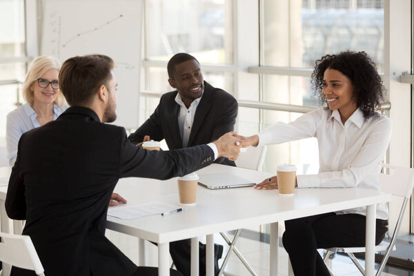 Различные бизнесмены пожимают друг другу руки во время встречи в офисе
