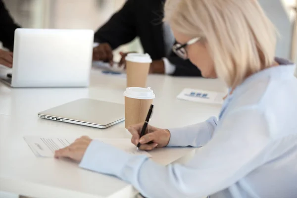 Volwassen zakenvrouw achter bureau ondertekening van een contract — Stockfoto