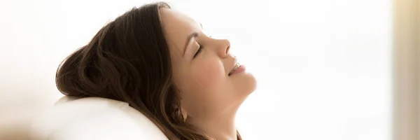 Panoramic side view woman face closed eyes resting on couch