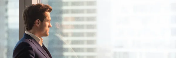 Panoramatický snímek podnikatel v obleku při pohledu přes okna kanceláře — Stock fotografie