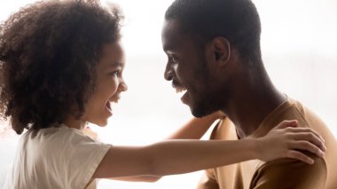 Mutlu aile şirin karma yarış çocuk kız siyah kucaklayan baba gülüyor