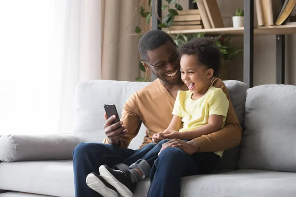 Feliz pai africano e filho da criança rindo olhando para o celular — Fotografia de Stock