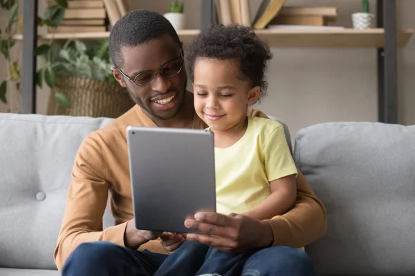 Feliz pai africano e pequeno filho usando tablet em casa — Fotografia de Stock