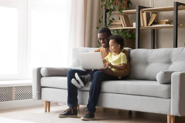 Jovem pai negro e filho miúdo usando laptop em casa — Fotografia de Stock