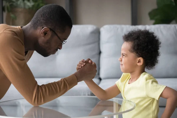 Afrikanischer Vater und Sohn mit lustigen, wütenden Gesichtern beim Armwrestling — Stockfoto