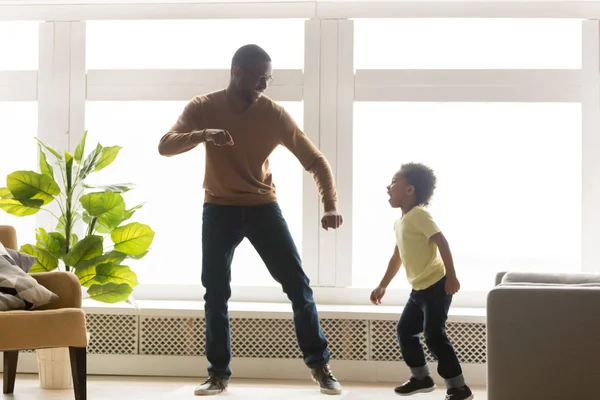 Glücklicher afrikanischer Vater und Kleinkind-Sohn tanzen im Wohnzimmer — Stockfoto