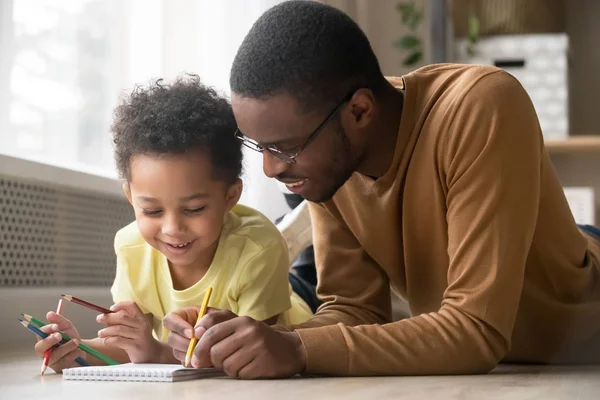 非洲爸爸和幼儿儿子用彩色铅笔画画 — 图库照片