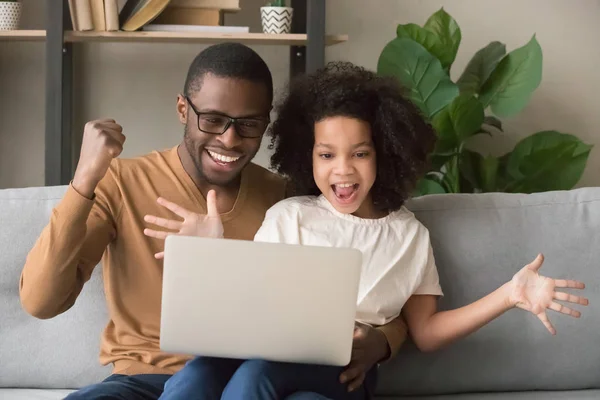 兴奋的非洲父亲和女孩优胜者看着笔记本电脑 — 图库照片