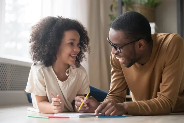 Afrikanska barn flicka ritar med pennor som har kul med pappa — Stockfoto