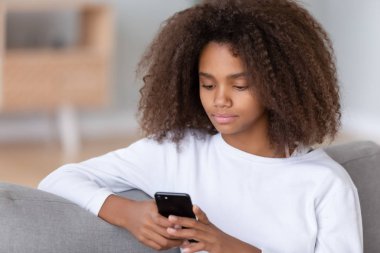 Afrika genç kız smartphone kullanarak kanepede oturan kapatın