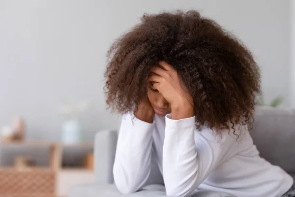 Menina adolescente africano infeliz pensando em problemas sentados no sofá — Fotografia de Stock