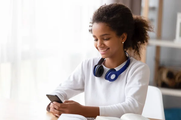 African teen girl distracted from study use smartphone — Stock Photo, Image