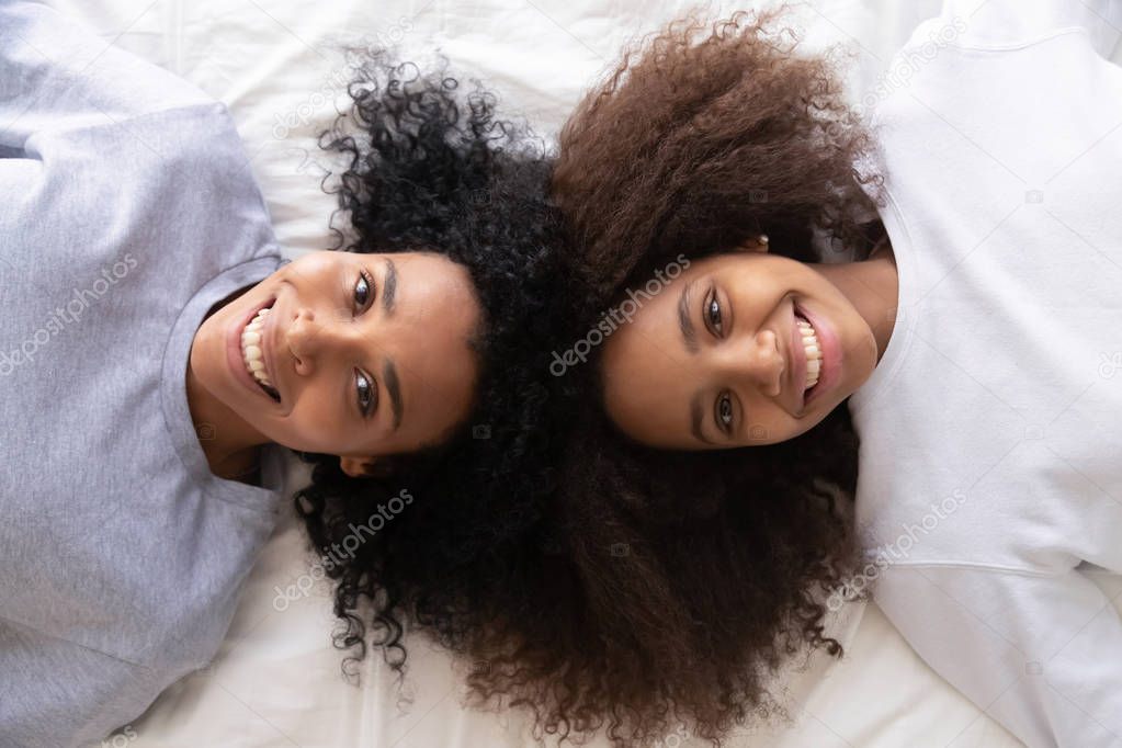 Above view african daughter and mother lying on bed