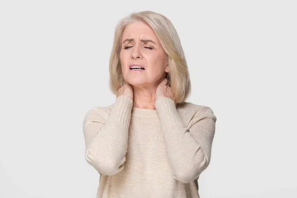 Upset mature woman massage feeling neck pain isolated on background — Stock Photo, Image